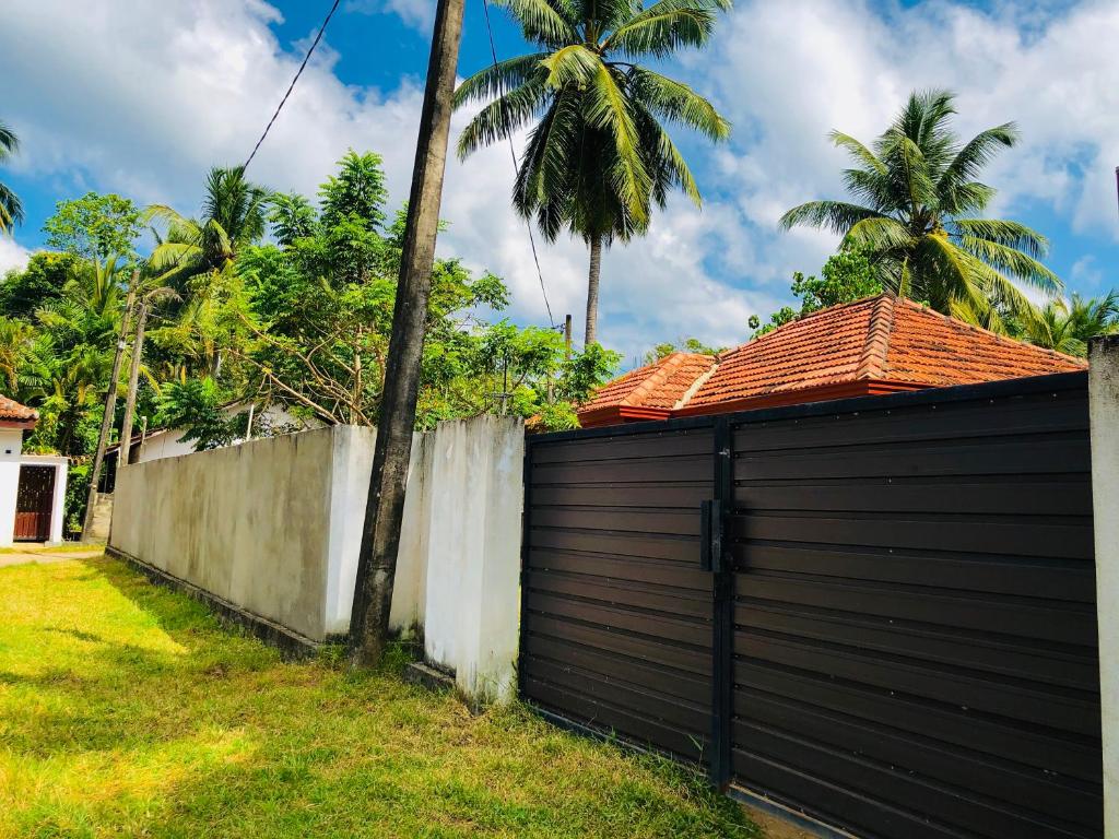 a black garage with a fence and palm trees at VILLA 826 Ahungalla in Ahungalla