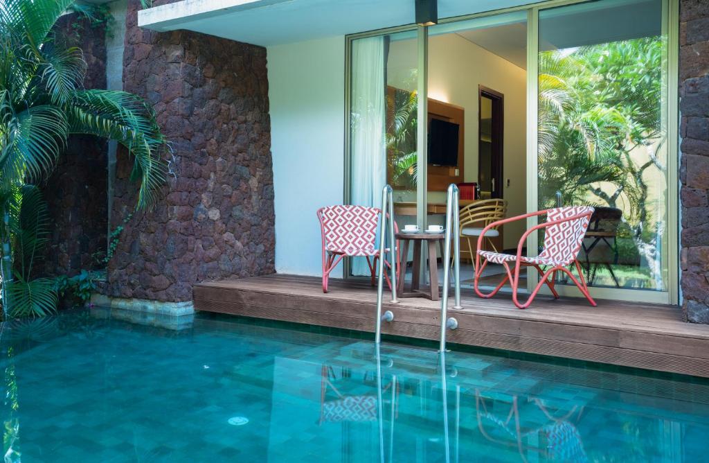 a patio with a table and chairs next to a swimming pool at MERUSAKA Nusa Dua in Nusa Dua