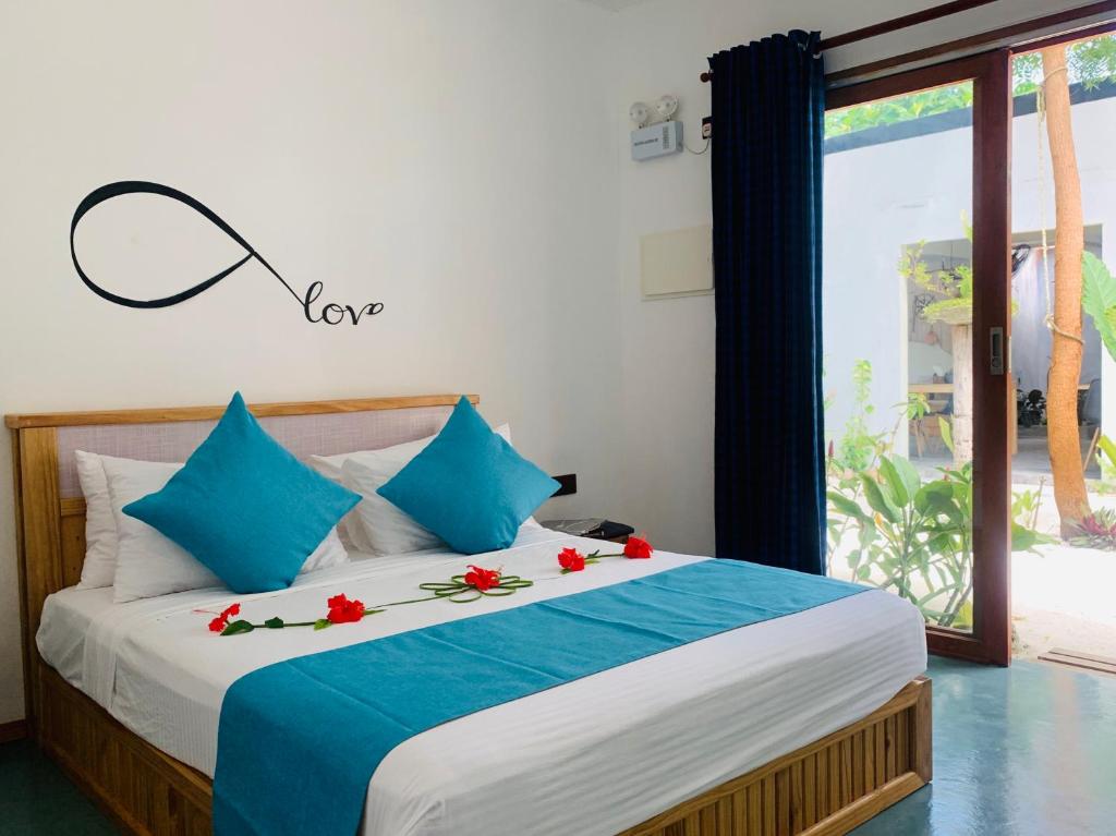ein Schlafzimmer mit einem Bett mit roten Blumen darauf in der Unterkunft Ithaa Thoddoo Inn in Thoddoo-Atoll