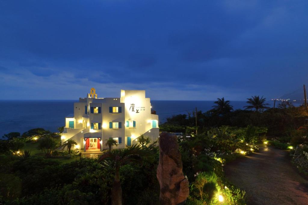 a large white house at night with the ocean in the background at 崖上民宿 Cliff House B&B in Fengbin
