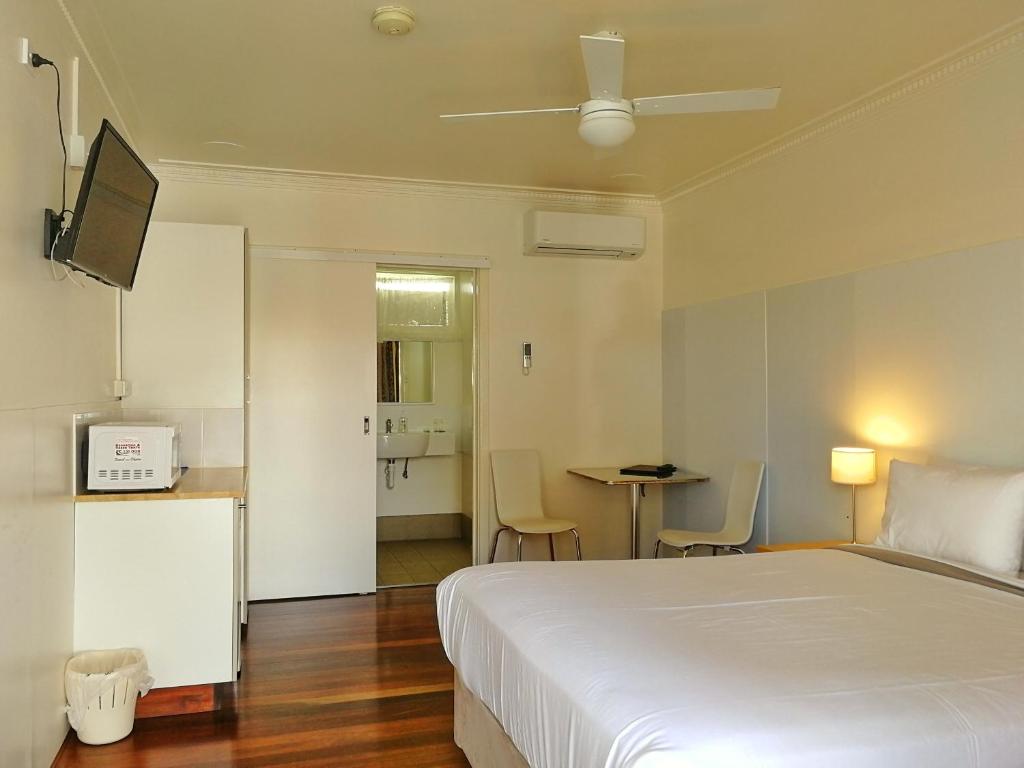 a bedroom with a white bed and a table with chairs at Ringtails Motel in Busselton