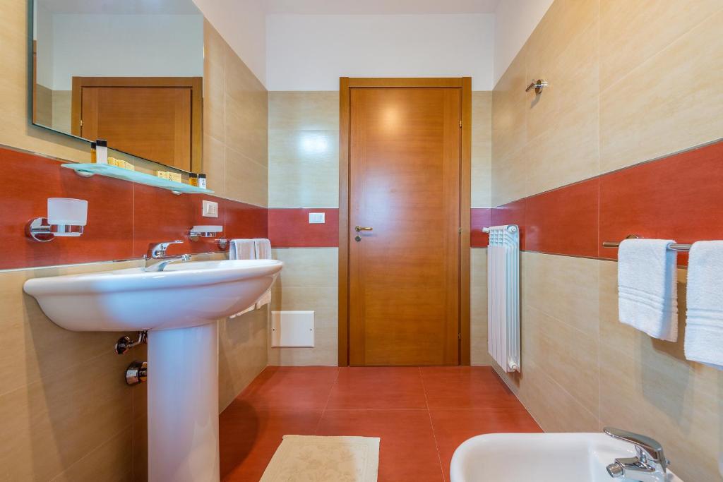 łazienka z umywalką, toaletą i lustrem w obiekcie GoodStay Archimede Apartment w mieście Lecce