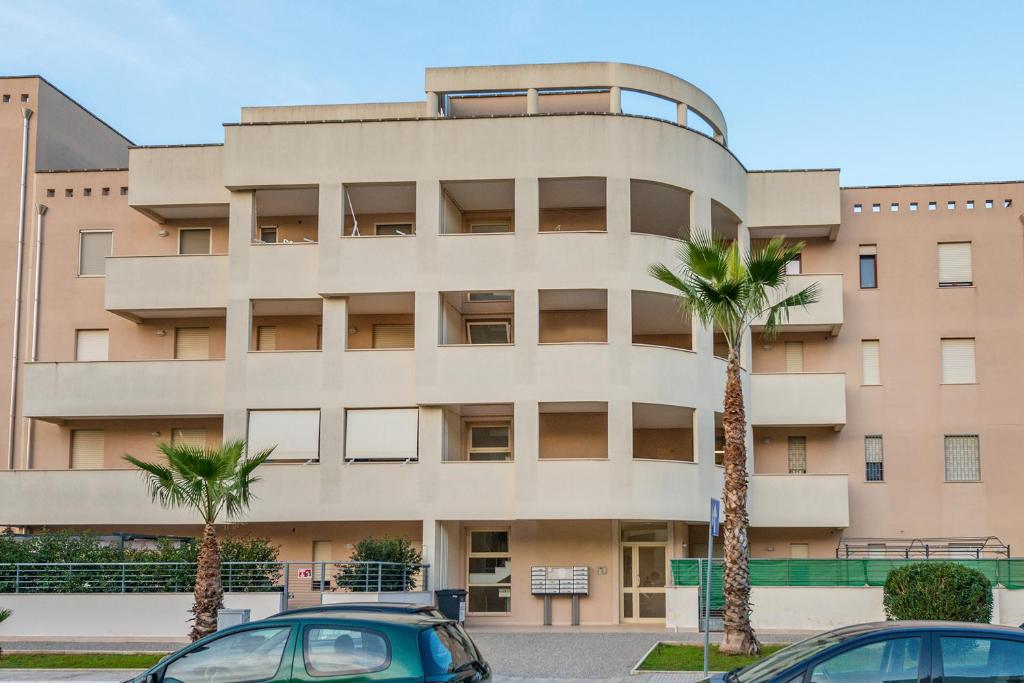 budynek z dwoma palmami przed nim w obiekcie GoodStay Archimede Apartment w mieście Lecce