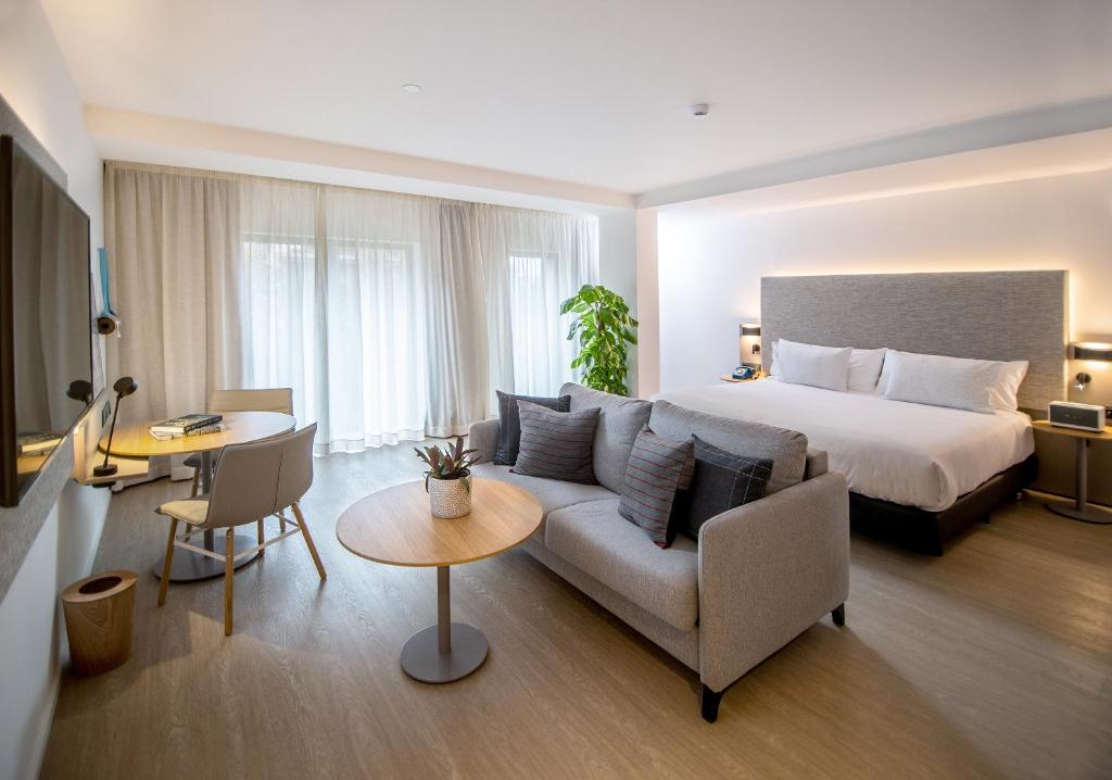 una camera d'albergo con letto, divano e tavolo di INNSiDE by Meliá Zaragoza a Saragozza