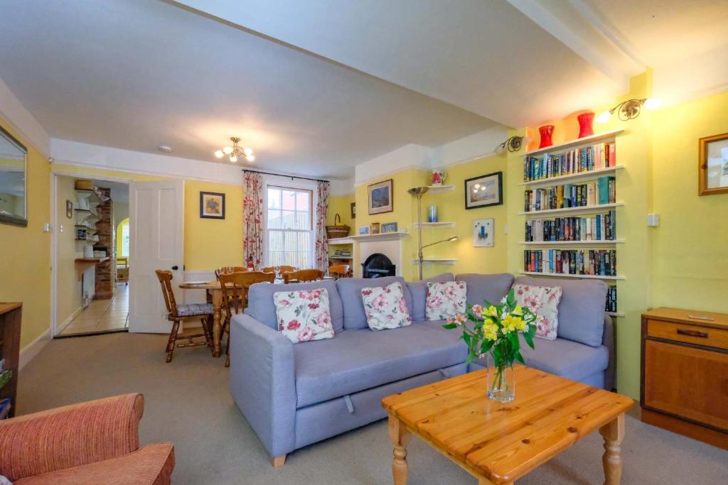 a living room with a blue couch and a table at 4 Old Homes, Thorpeness - Only a stones throw from the beach - Aldeburgh Coastal Cottages in Thorpeness