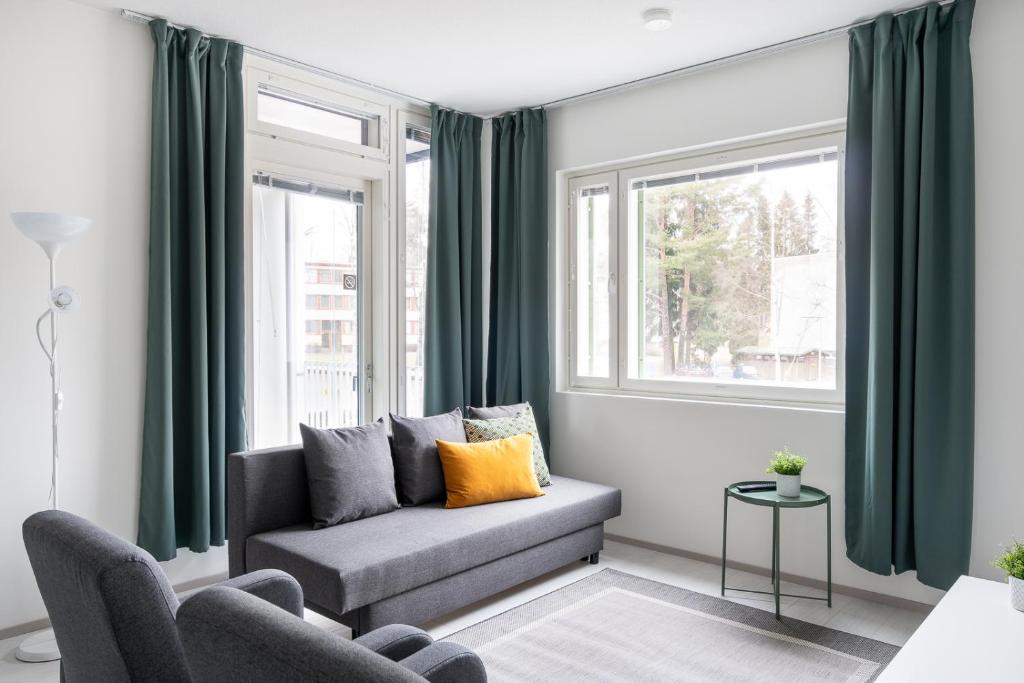 a living room with a couch and two windows at Hiisi Homes Vantaa Kaivoksela in Vantaa