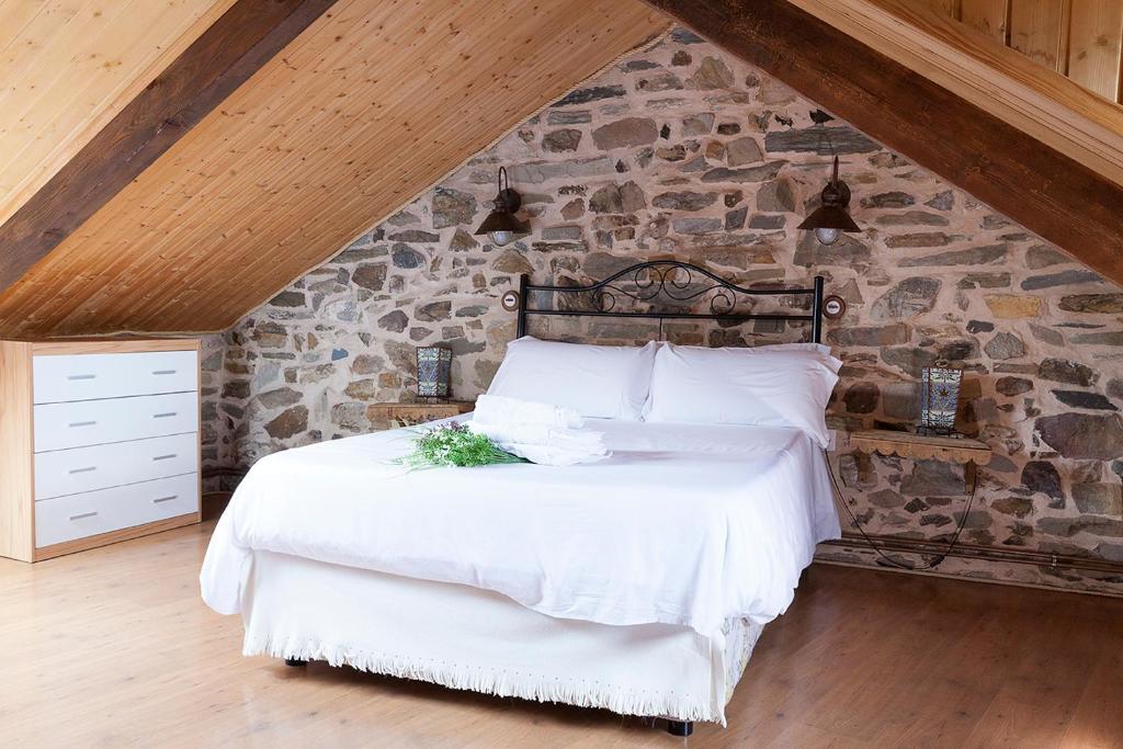 a white bed sitting in a room next to a wall at La Rosa del Agua in El Acebo de San Miguel