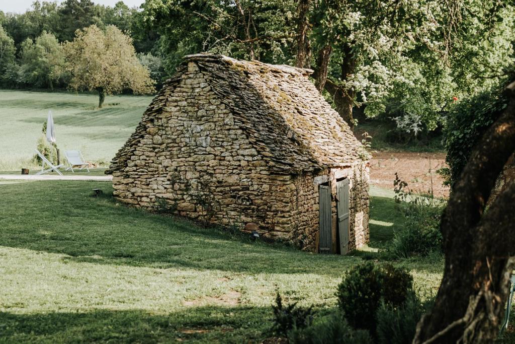 um pequeno edifício de pedra num campo de relva em Maison d'hôtes Bel Estiu em Saint-Geniès