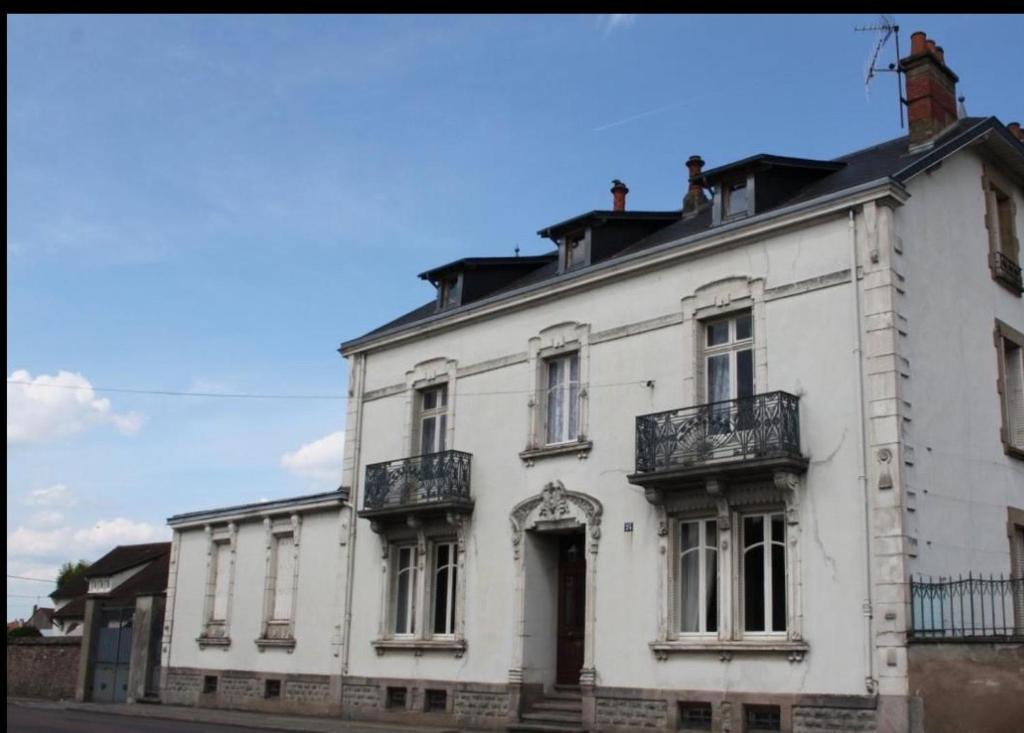 an old white building with a balcony on a street at Augustodun'Home in Autun