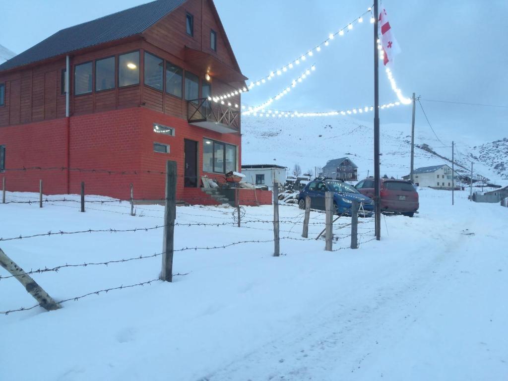 a red building with a fence in the snow at family hotel Mtamta in Gudauri