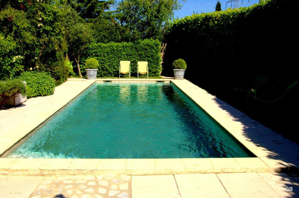 una piscina con 2 sillas en un patio en Le GITE du MAS des CLOTS, en Upie