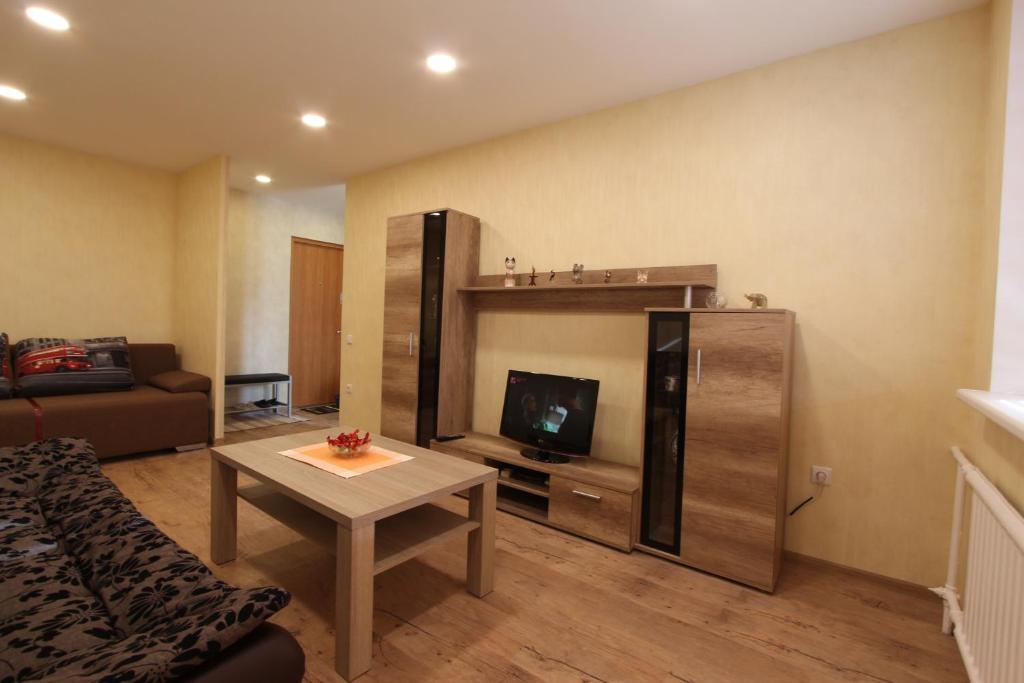 sala de estar con sofá, mesa y TV en Sondeckio Apartment, en Šiauliai