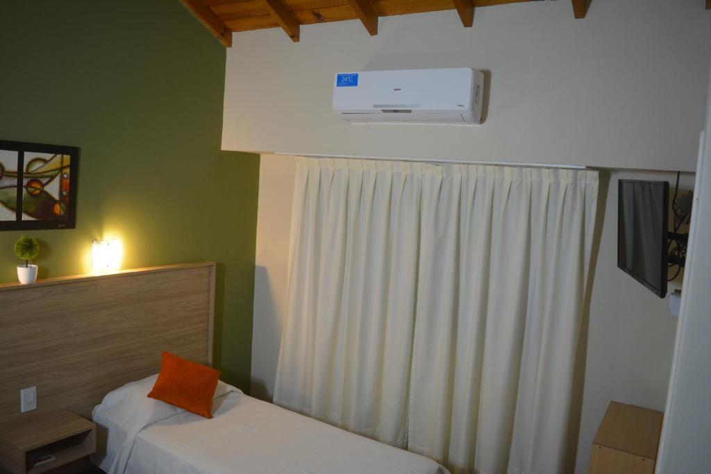 a bedroom with two beds and a window with a heater at Hotel Fariña in Mar de Ajó