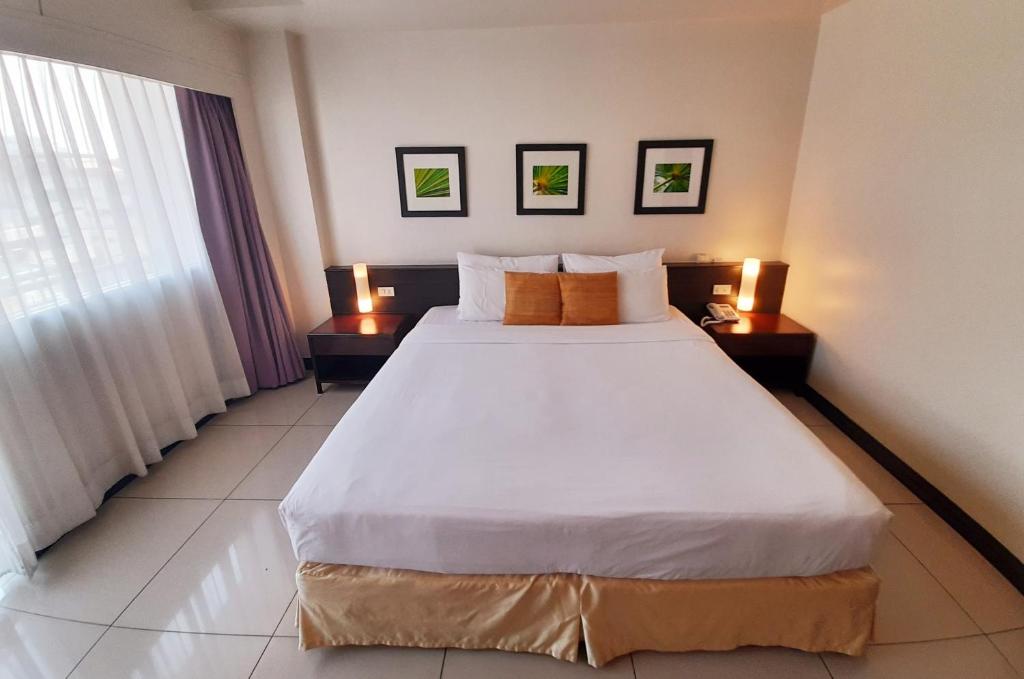 a bedroom with a large white bed with two tables at Grand Hotel in Pattaya South