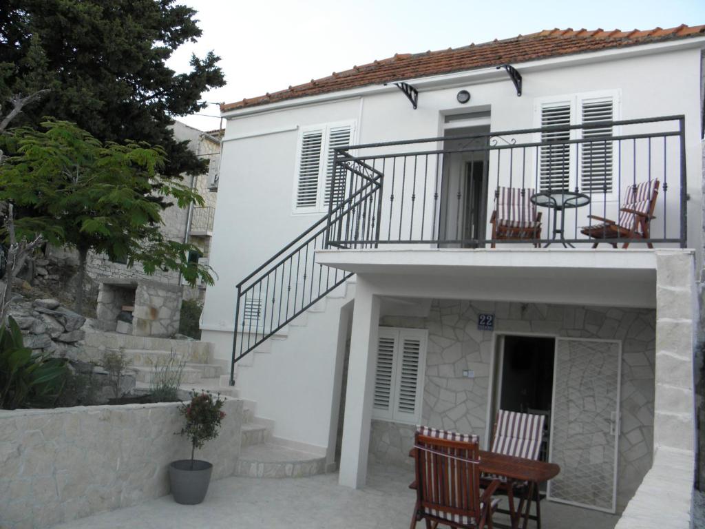 a white house with chairs and a balcony at Apartmani Adam in Primošten