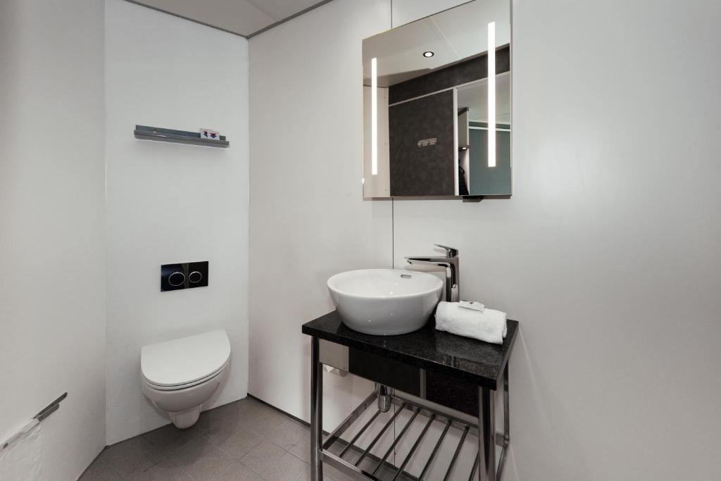 a white bathroom with a sink and a toilet at Cabinn Copenhagen in Copenhagen