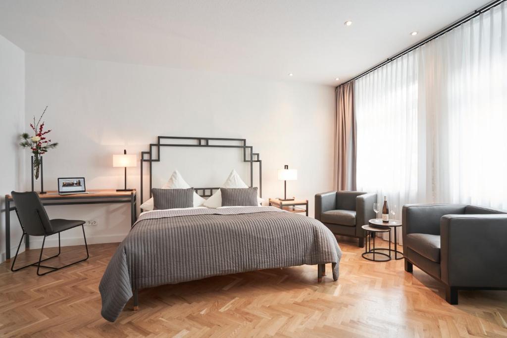 een slaapkamer met een bed en 2 stoelen bij Hotel Goldener Engel in Speyer