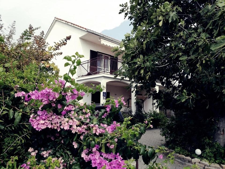 Uma casa branca com flores cor-de-rosa à frente. em Holiday House Maja em Podglavica