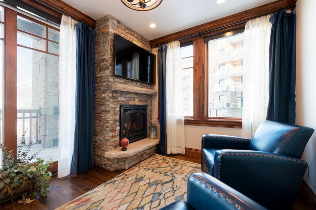 a living room with a fireplace and a blue chair at Silver Strike Lodge #201 - 2 Bed in Park City