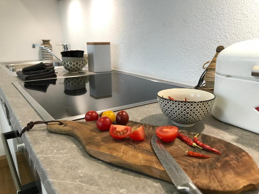 uma tábua de cortar com tomates e uma faca no balcão em Ferienwohnung Maria em Überlingen