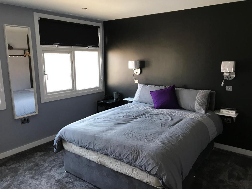 a bedroom with a large bed and two windows at Cozy Rooms in Liverpool