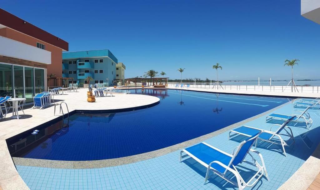 a large swimming pool with chairs and the beach at Arraial do cabo golden Lake in Arraial do Cabo