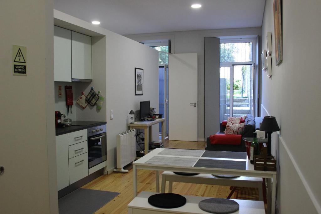 a kitchen and living room with a table in a room at Practical and Comfortable Apartment with Garden in Porto