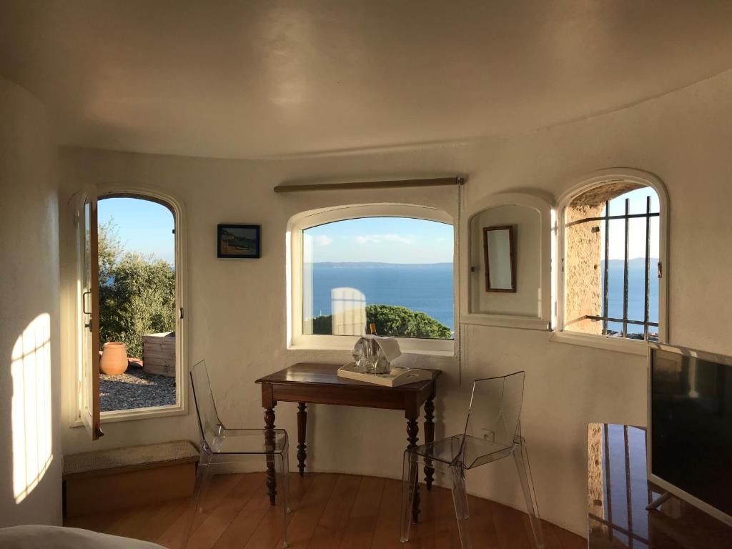 a room with two windows and a table with a view at B&B La Sergerie in Le Lavandou