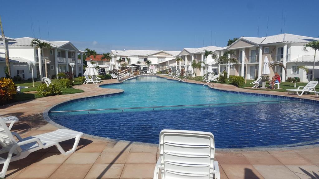 ポルト・セグロにあるCondomínio Mar da Galiléia - Apto 27の椅子2脚といくつかの家があるプール