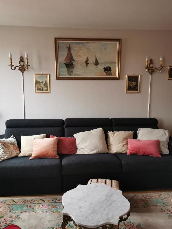 a living room with a blue couch with colorful pillows at Suite Clémenceau 82 in Reims