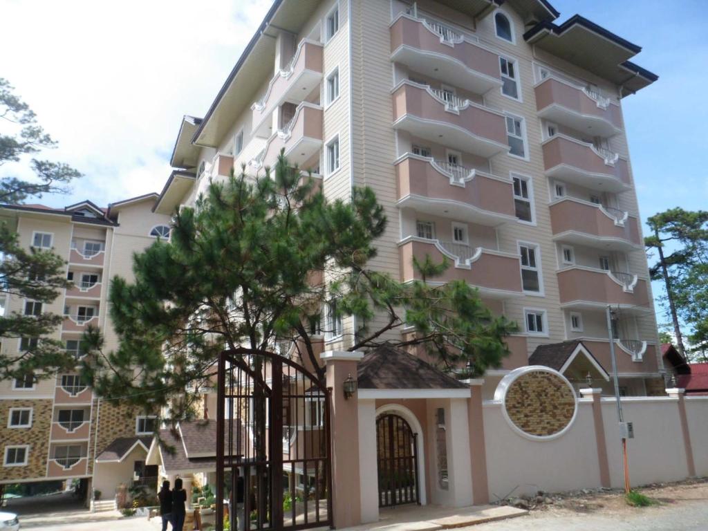 un edificio con un árbol delante de él en Prestige Vacation Apartments - Bonbel Condominium en Baguio