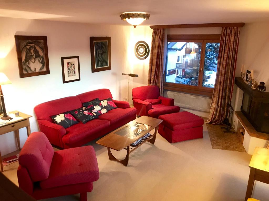 ズルレイにあるApartments Chesa Guardavalのリビングルーム(赤いソファ、赤い椅子付)