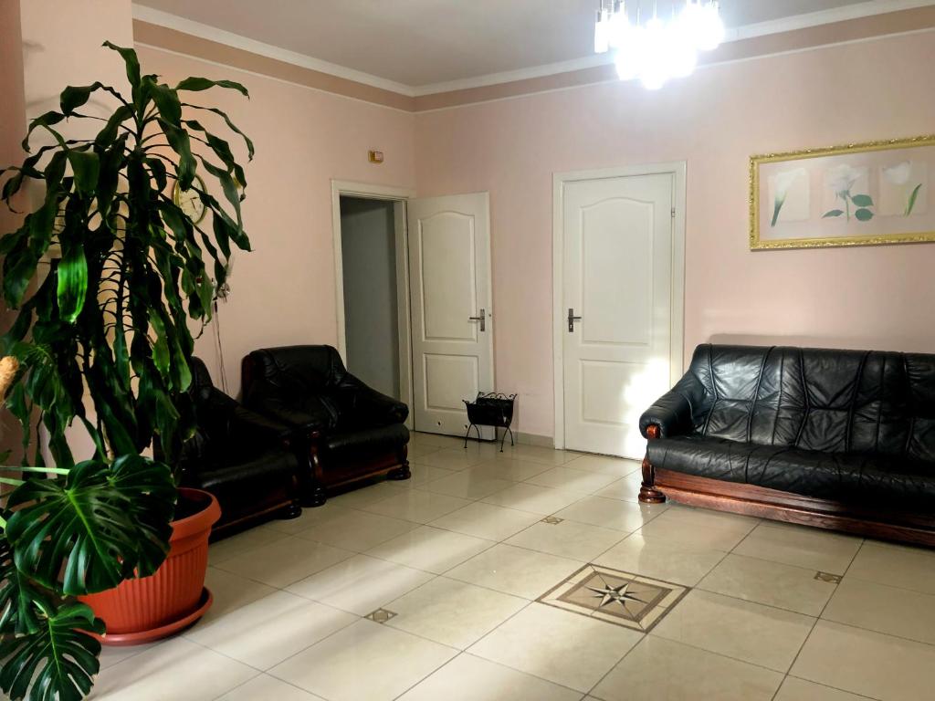 una sala de estar con 2 sofás de cuero negro y una planta en Comfort Hotel, en Chervonograd