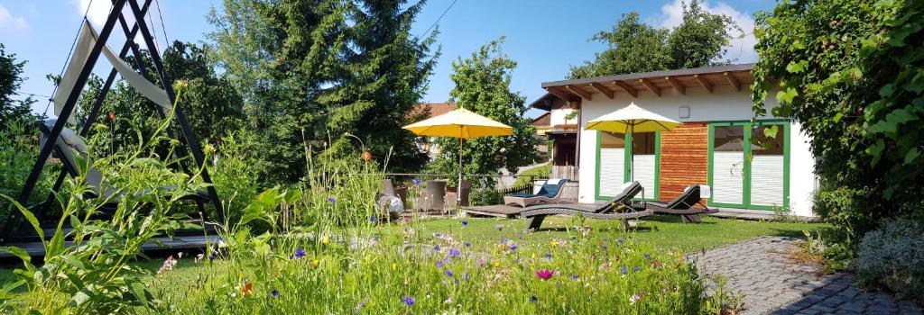 a garden with two chairs and a table and yellow umbrellas at BIO Appartement Resort in Bodenmais