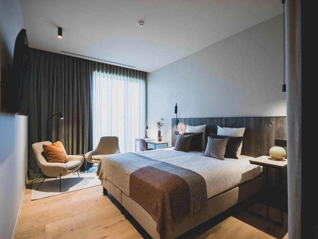 a bedroom with a large bed and a chair at Waer Waters Spa Hotel in Groot-Bijgaarden