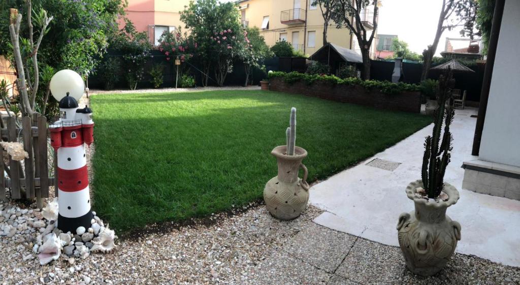 een tuin met een vuurtoren en twee vazen met planten bij Shell House, Casa con ampio giardino a 100m dal mare in Marcelli