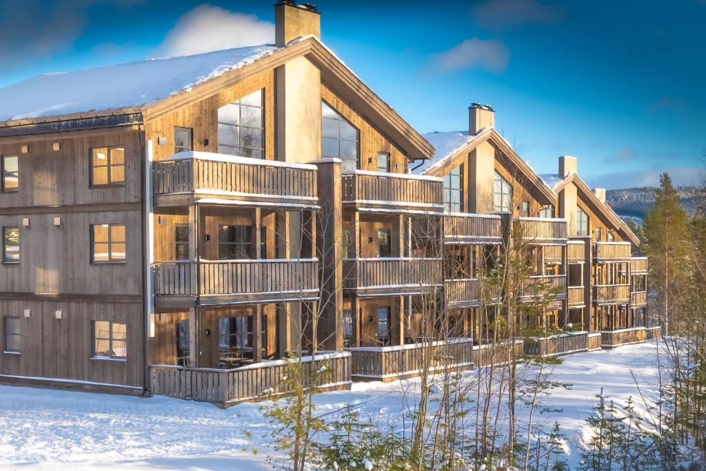 a large wooden building with snow on the ground at Trysiltunet 16b in Trysil