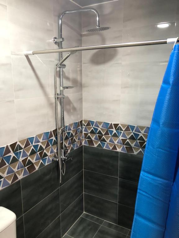 a shower with a blue shower curtain in a bathroom at Wander Kazbegi Hotel in Stepantsminda