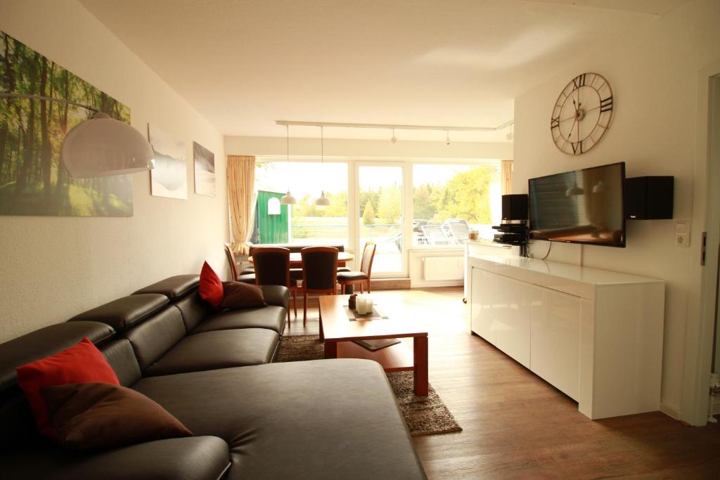 ein Wohnzimmer mit einem Sofa und einer Uhr an der Wand in der Unterkunft App 613 Panoramic Hohegeiß Terrassenhaus in Hohegeiß