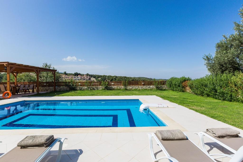 ein Pool in einem Garten mit Stühlen um ihn herum in der Unterkunft GreenLand Villa in Khoumérion