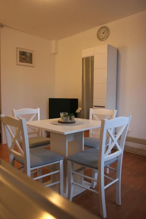 a white dining room table and chairs with a clock on the wall at STUDIO APARTMAN MARIA in Čavle