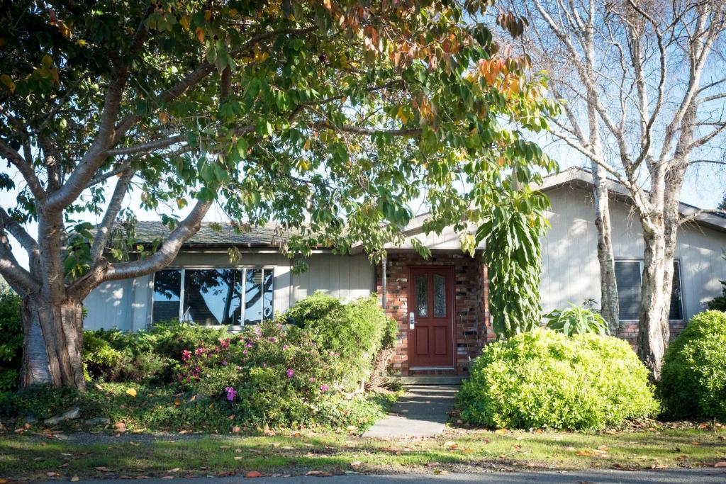 a white house with a red door and trees at Trinidad Village Retreat in Trinidad