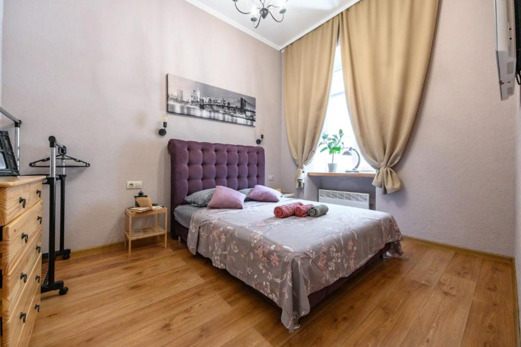 - une chambre avec un grand lit et une tête de lit violette dans l'établissement Тихие апартаменты недалеко от Дерибасовской, à Odessa
