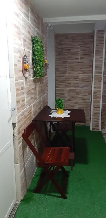 una mesa y un banco en una habitación con alfombra verde en Quarto com suíte para mulheres en Río de Janeiro