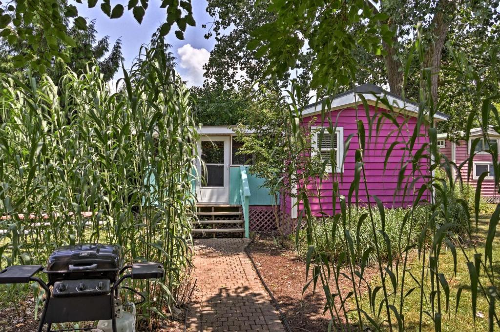 a pink and blue caravan in the middle of a garden at Cozy Middle Bass Cabin with Grill and Lagoon Access! in Put-in-Bay