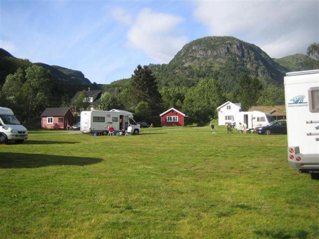 a field with houses and a mountain in the background at Seim Camping - Røldal in Røldal