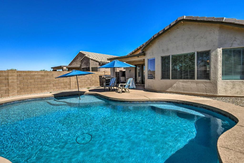 - une piscine avec deux parasols en face d'une maison dans l'établissement Gold Canyon Retreat with Superstition Mountain Views, à Gold Canyon