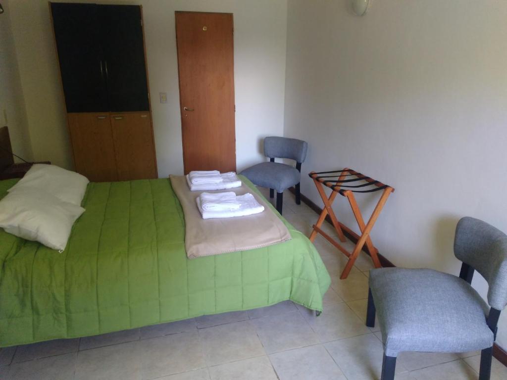 a bedroom with a green bed and two chairs at Don Alfonso Departamento in San Carlos de Bariloche