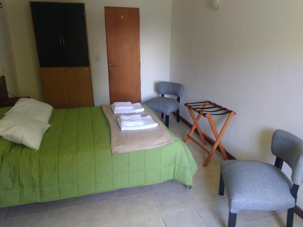 1 dormitorio con 1 cama verde y 2 sillas en Don Alfonso Departamento, en San Carlos de Bariloche