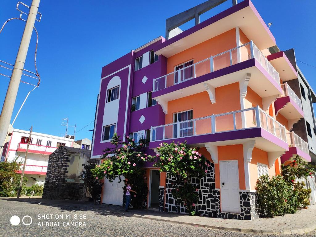 een kleurrijk gebouw waar een vrouw voor staat bij Casa Celeste in Ponta do Sol